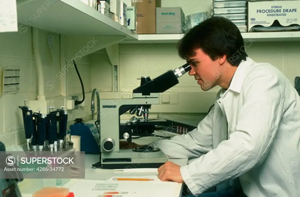 Man uses microscope in bio-medical lab