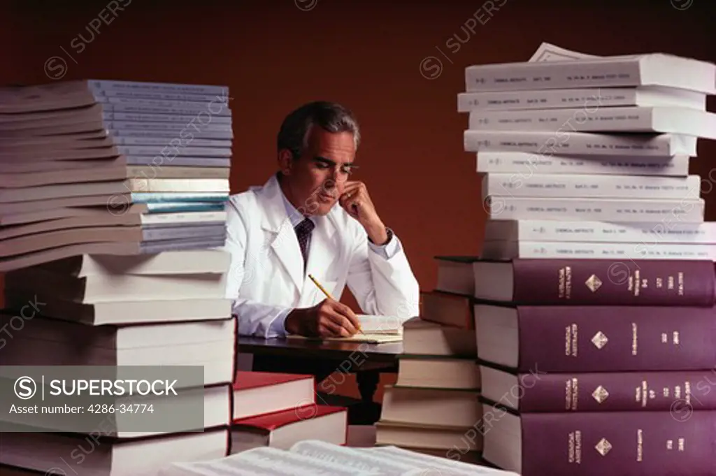 Chemist looks up information through pile of papers