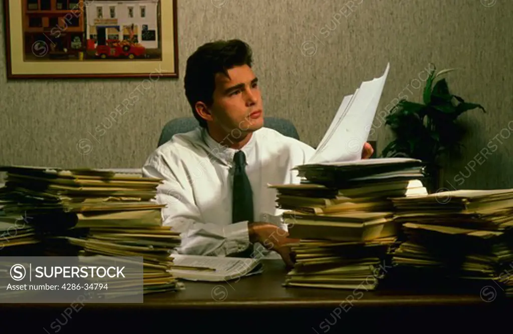 Man wades through paperwork in office