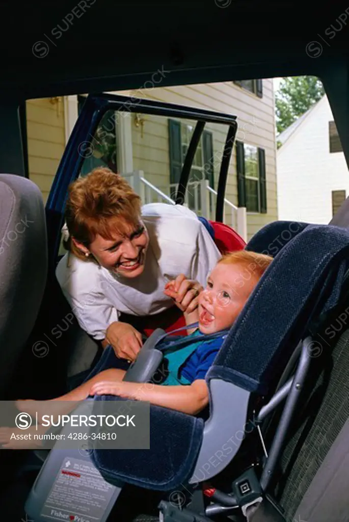 Meg Bowel strapping son into baby car seat.