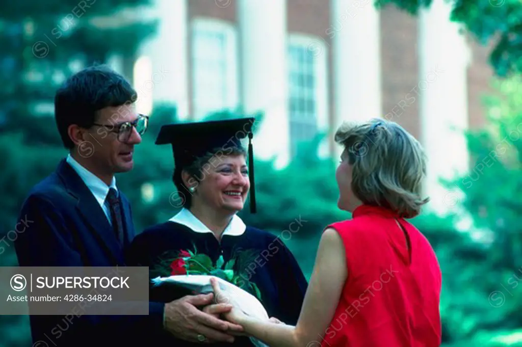 A mother graduating from college receives congratulations from her daughter and husband