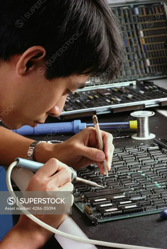 Vietnamese worker repairs circuit board at Filenet in Costa Mesa, CA (released). - BC 2737