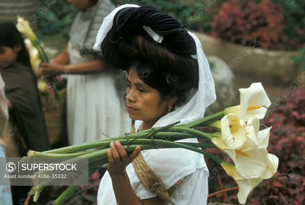 Mexico, Puebla State: Indian woman with flowers at Sunday market in small town: Cuetzalan.