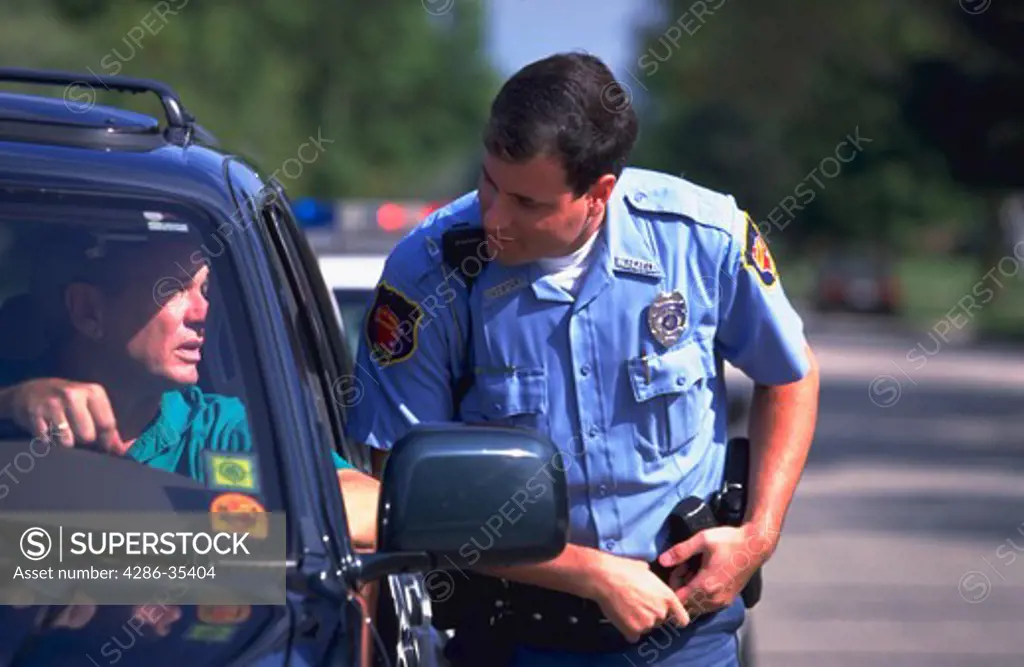 Police officer approaches the driver of a car after stopping him for a traffic  violation.