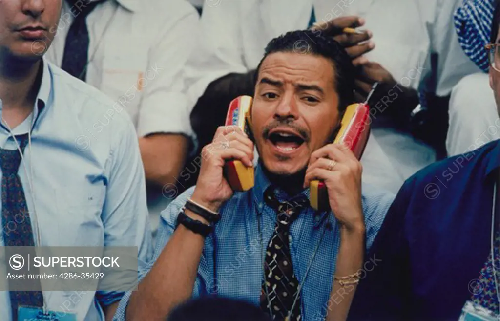 Male pit trader using two different telephones while yelling to place trades on the floor of the Bolsa de Mercadorias and Futures Exchange, Sao Paulo, Brazil.
