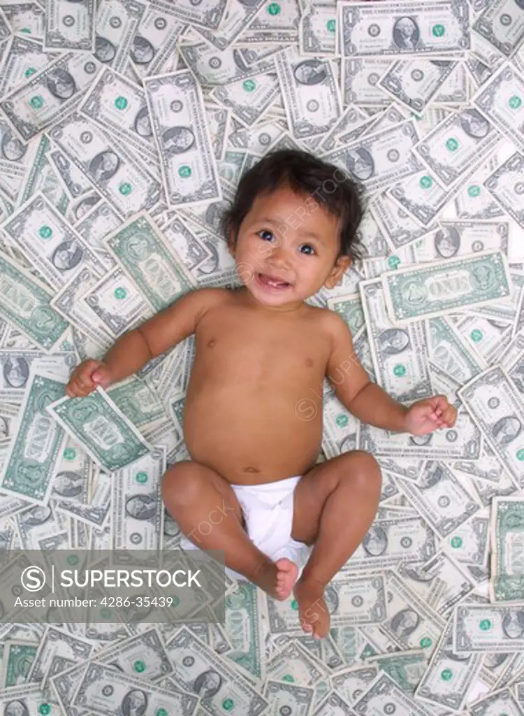 Southeast Asian Cambodian eleven month old baby girl lying in a pile of money.