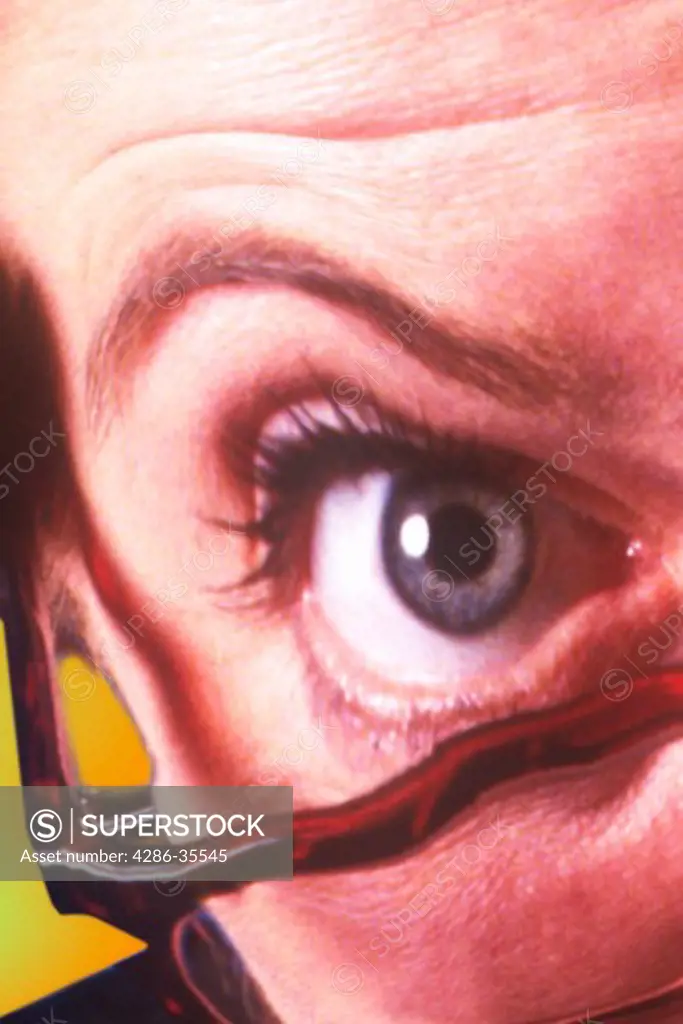 Distorted image of a womans eye and raised eyebrow looking out from behind glasses.