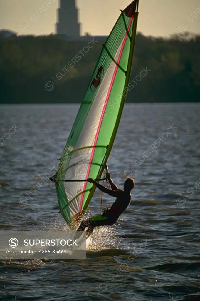 Sailboarding, action shot with man and colorful sail.  Also, called windsurfing.  Shot on the Potomac River, near Washington, DC.  (Recreation.  Water Series.)