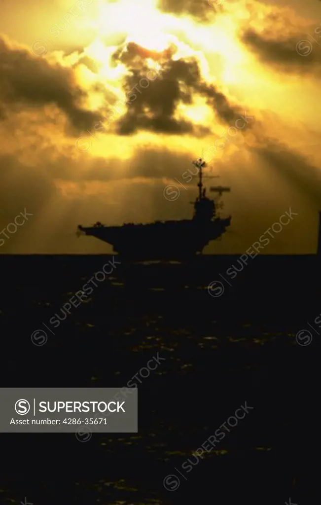 U.S. Navy aircraft carrier, operating in the Pacific Ocean.  Dramatic shot with interesting sky.  Taken from second ship, a U.S. Navy frigate following the carrier during a lull in flight operations, while in a plane guarding role.(Water Series. Ocean.  Military. National Security.)
