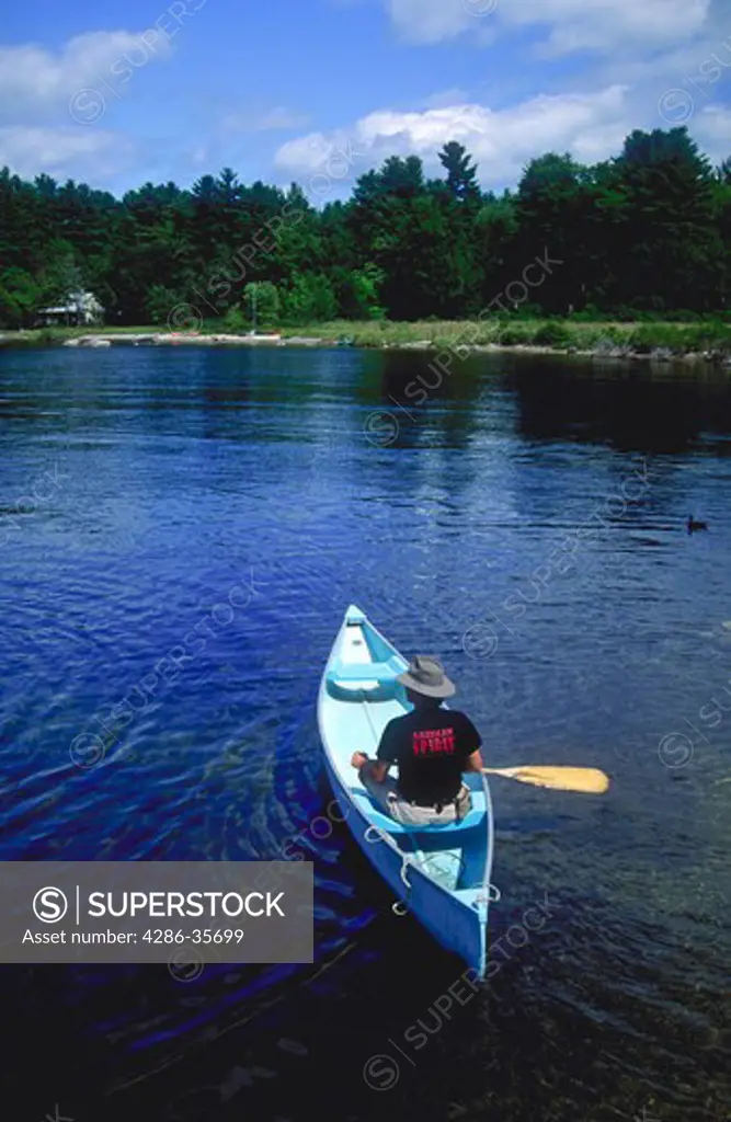 Man in blue canoe on Sebago Lake in Maine.  Paddle extended to the right, canoe gliding into the scene.  Personal discovery.  Quality time alone.  Peaceful and relaxing, although physical effort is required.