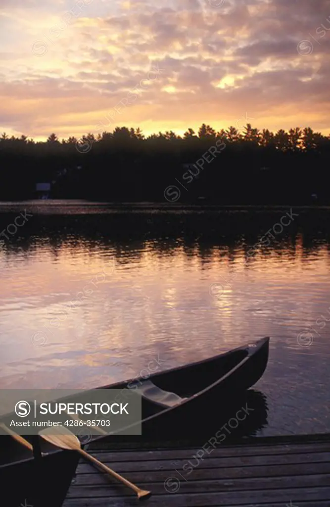 Canoe, alongside small dock on Sabbathday Lake in Maine.  Early morning, just before sunrise.  John Hartman has a large file of canoe and boating images. 