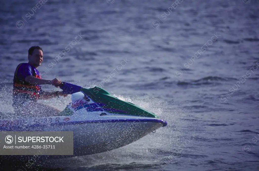 Man riding on a personal watercraft (PWC, also known as jet ski or waverunner.).  Taken on Rehoboth Bay, Delaware.