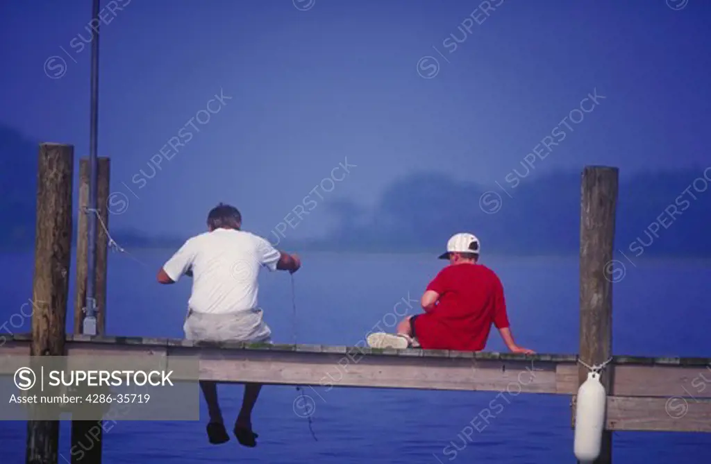 Man and boy (father and son), sitting on a dock in the bay.  Taken in summer on Rehoboth Bay, Delaware. 