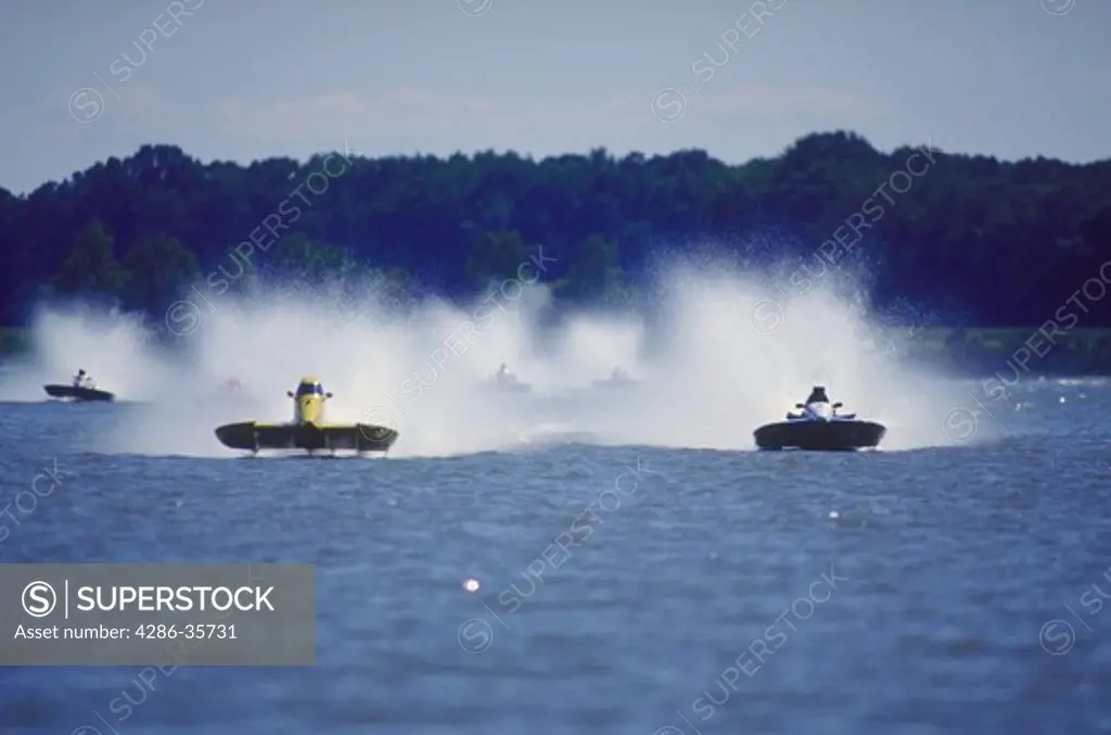 Hydroplane boats racing.  Waterspray is flying above the boats as they are head-to-head coming straight toward the camera, prior to making the first turn on the race course.  Taken at the Chesapeake Bay's Kent Narrows during a race which was part of a professional series. 