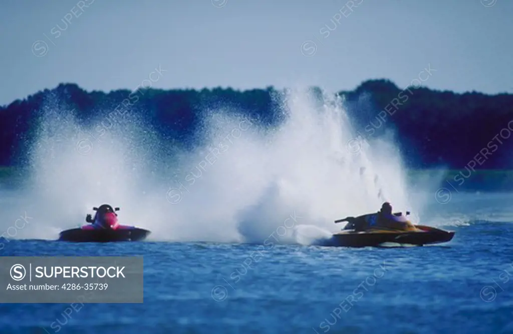 Hydroplane boats, racing.  Waterspray is flying as the boats approach the first turn on the racecourse, during a professional race at Kent Narrows on the Chesapeake Bay.  