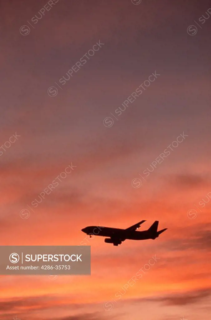 Airplane in flight, with colorful sky.  Commercial airliner.  (Aviation. Skies. Transportation.)