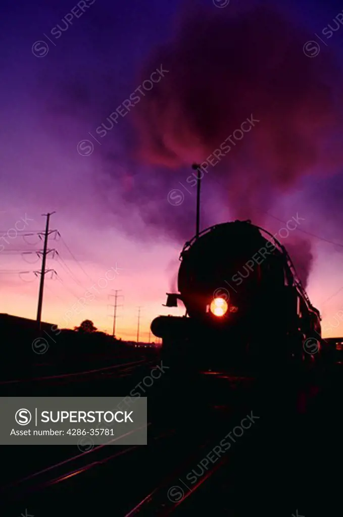 Old time steam locomotive, billowing steam and smoke, moving down the railroad track.  The engine is the No. 1218. (Concept. Americana. Built Tough. Nostalgia. Good old days. Transportation.)