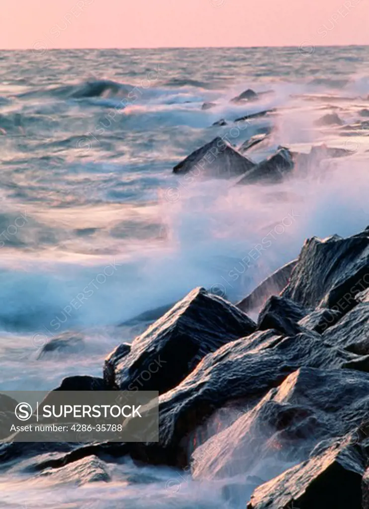 Ocean and waves, splashing on rocks, in early morning light.  Other variations available. (Landscape. Scenic. Water. Travel.)