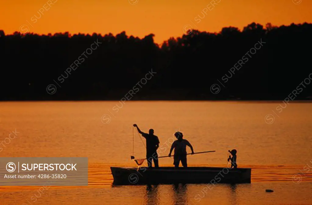 Silhouette of family fishing at sunset.