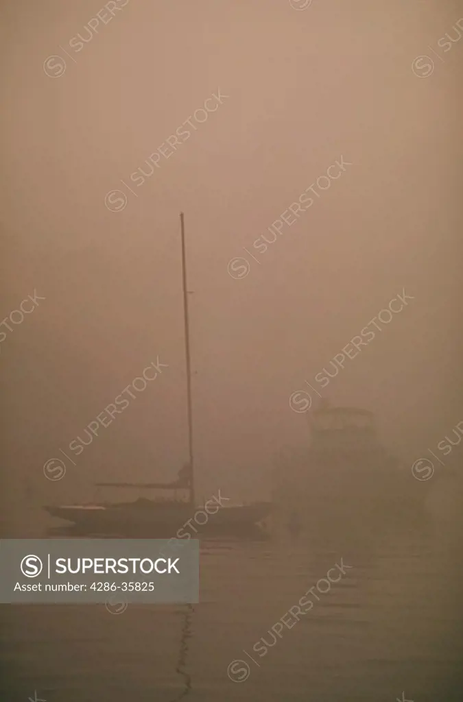 Sailboat and power boat in morning mist.