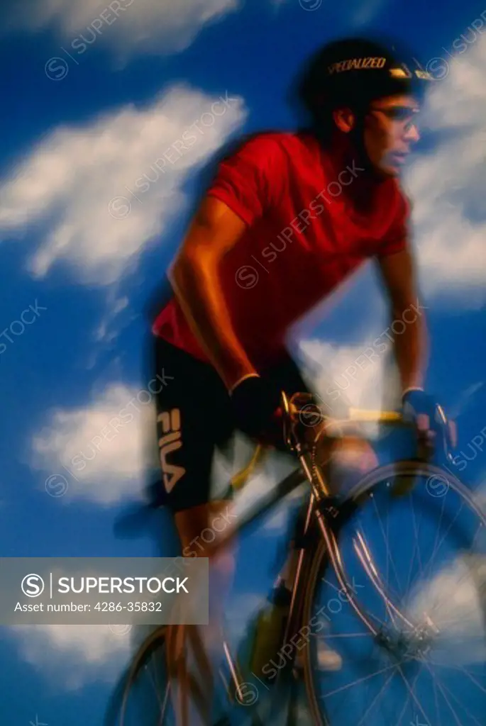 Man riding bicycle with blue sky and clouds.