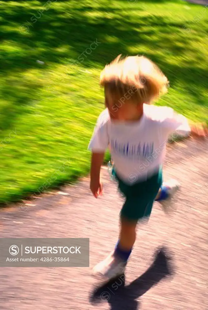 Young boy running on sidewalk.