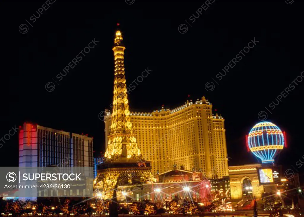 Eiffel Tower replica lit with neon lights in front of the Paris Hotel at night on the Las Vegas strip.