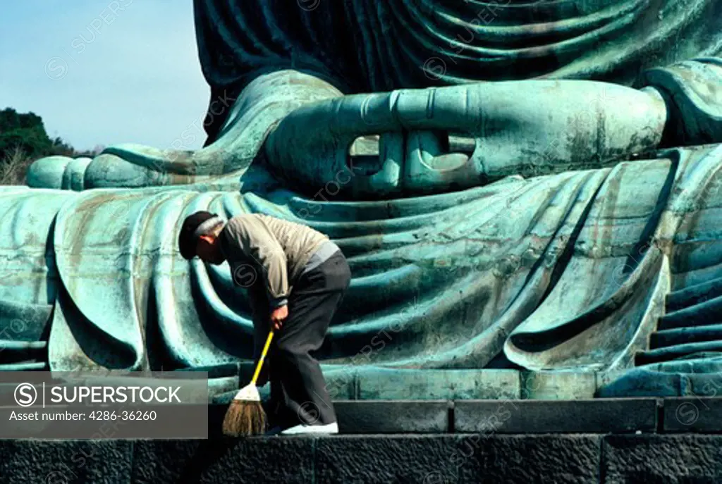 A caretaker is cleaning the massive Great Buddha (Daibutsu) statue in Kamakura, Japan.