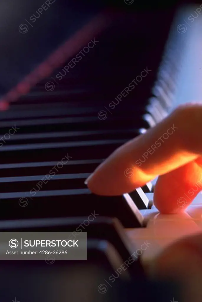 Close-up of black and white piano keys while two fingers are playing.