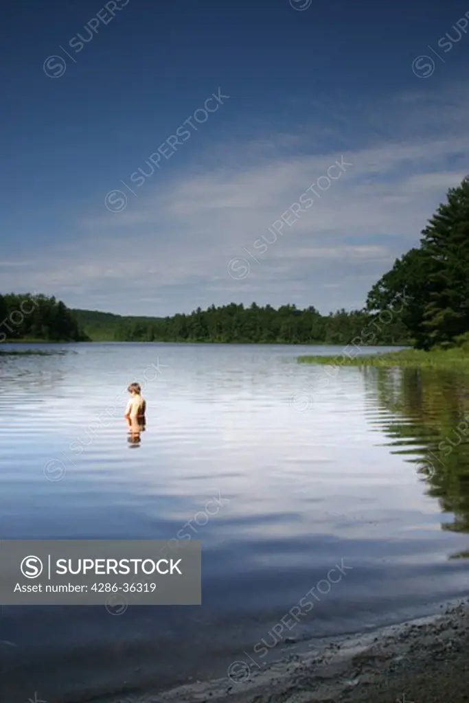 Young boy goes for a dip in a lake during the morning hours. 