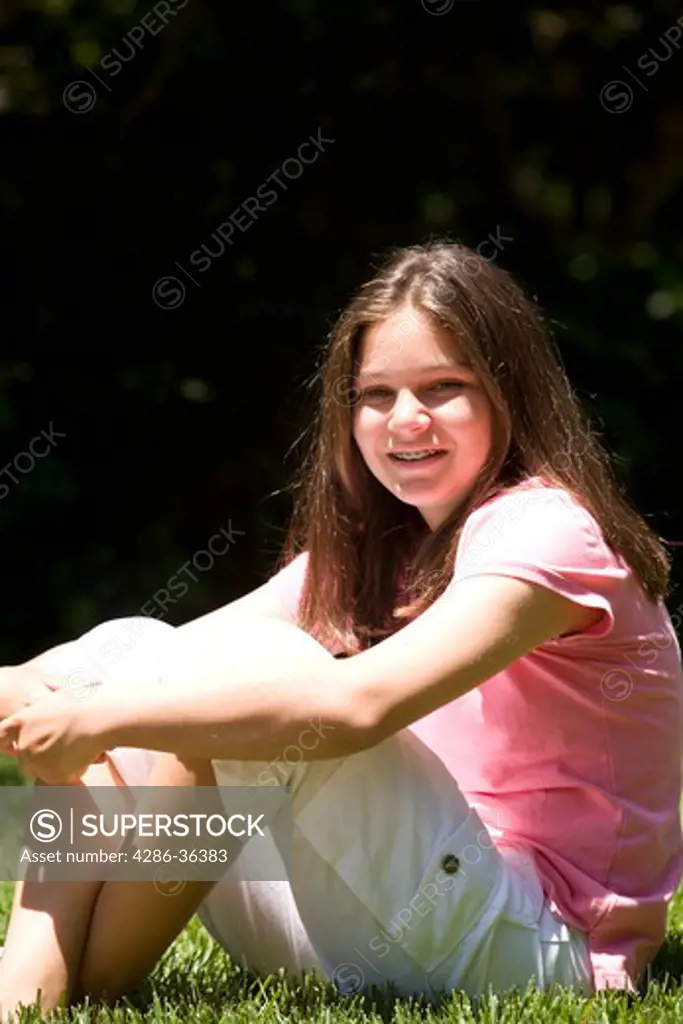 Laughing teen girl sitting on the grass