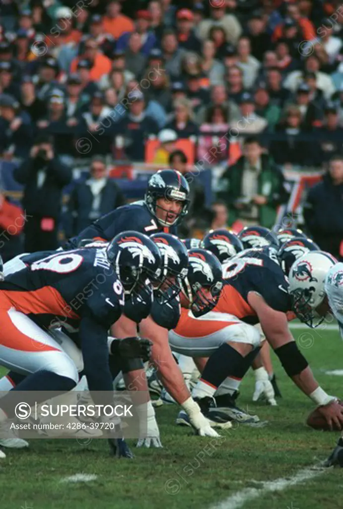 Denver Broncos line up for snap to QB John Elway during game against Miami Dolphins at Mile High Stadium, Denver, CO.