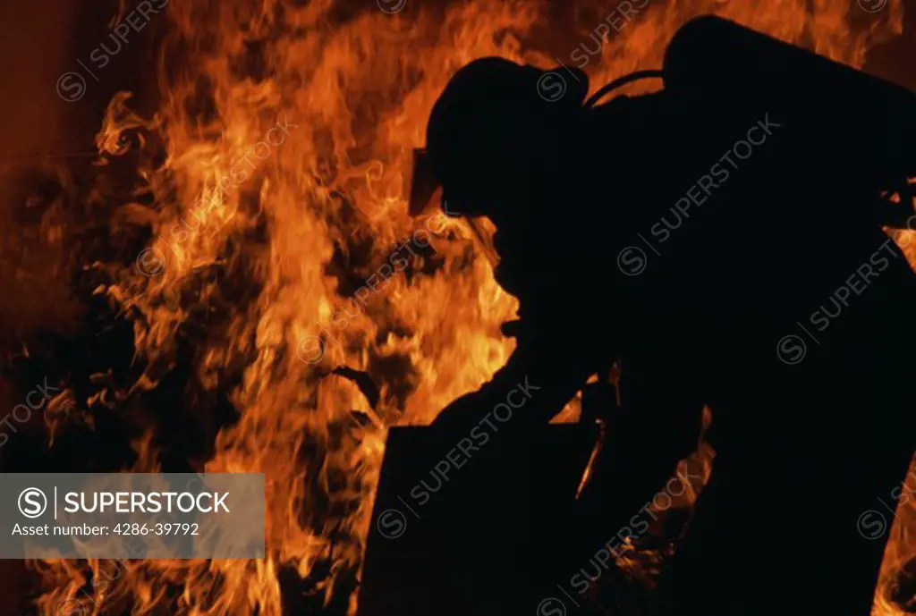 Silhouette of a firefighter with flames blazing around him. 