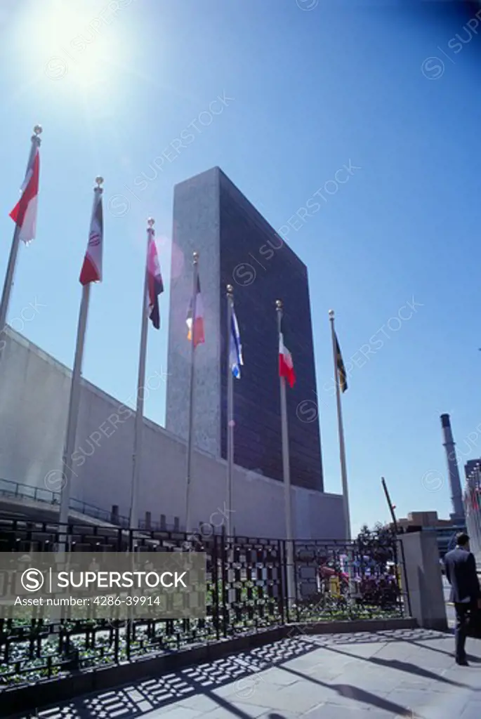 Exterior view of United Nations Secretariat and General Assembly buildings with flags in foreground. New York City. 