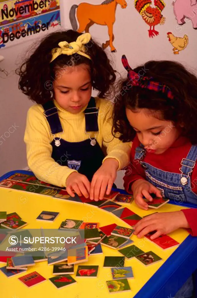 4-year-old twin sisters playing with puzzle.