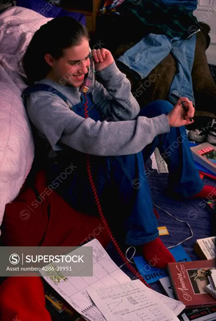 Teenage girl talking on phone in bedroom.