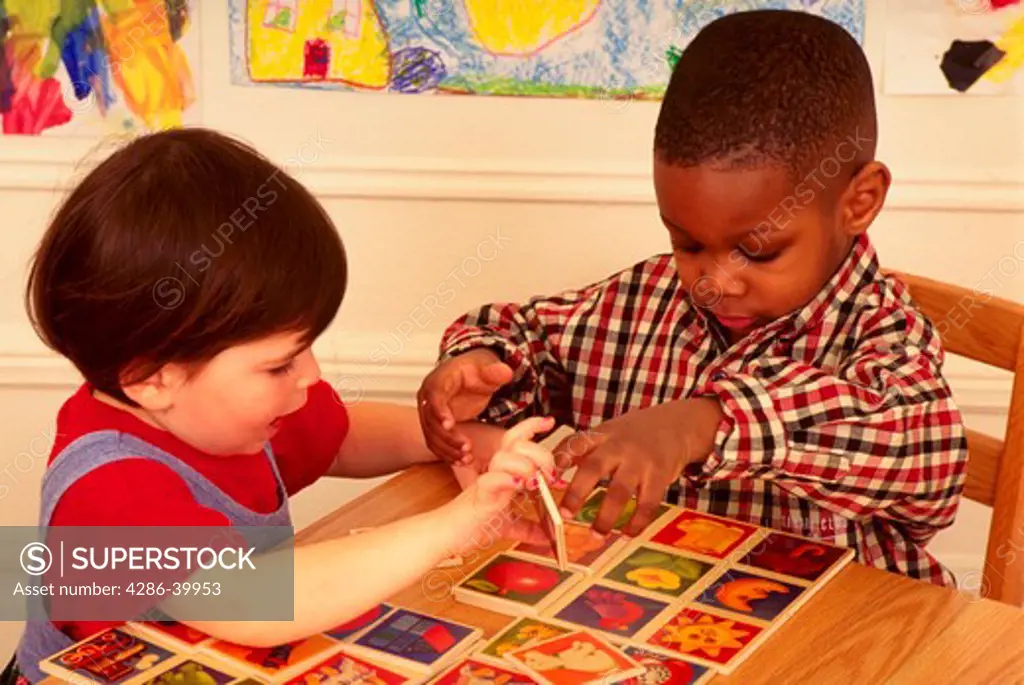 Young African American boy and young white girl playing with puzzle together.