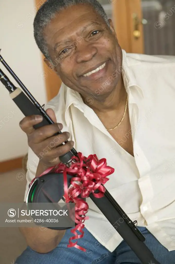 Senior, African American. Receiving fishing rod as gift.  MR-0509 PR-0505