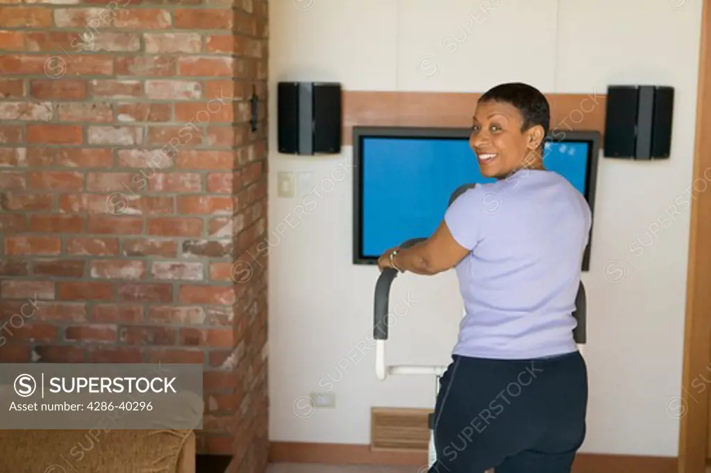 Senior, African American, exercising on stepper machine and plasma TV  MR-0510 PR-0505