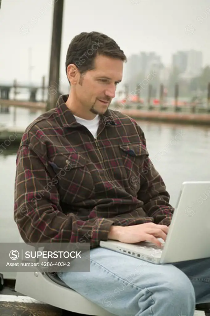 Man working on laptop in small boat.  MR-0422 PR-0424