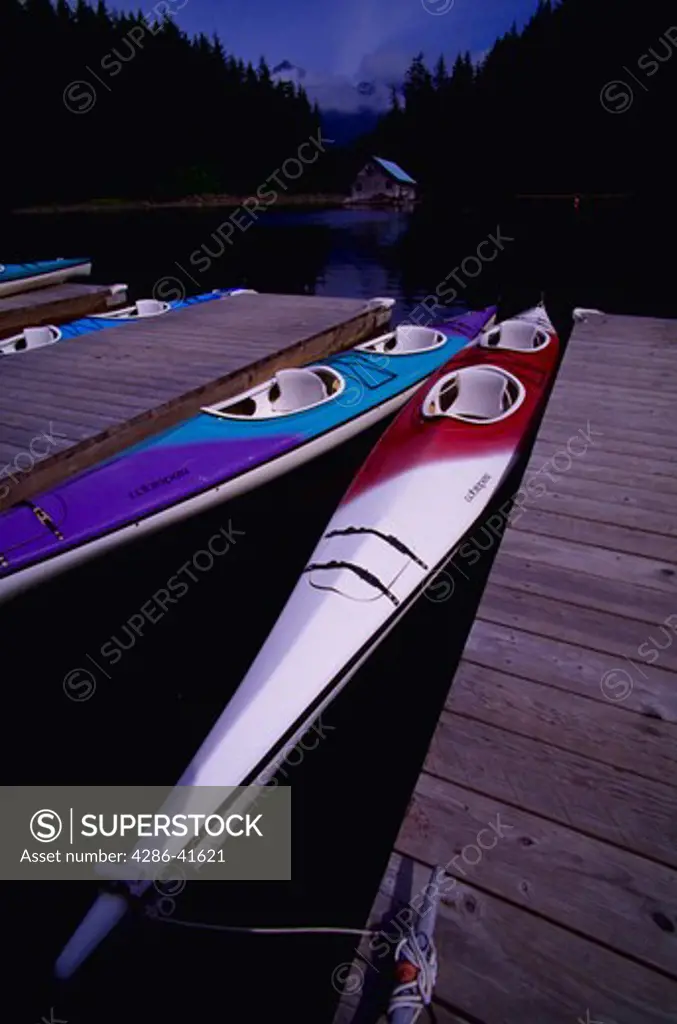Kayaks at docks with boathouse and mountains in background, Sitka Sound, Sitka, Alaska.