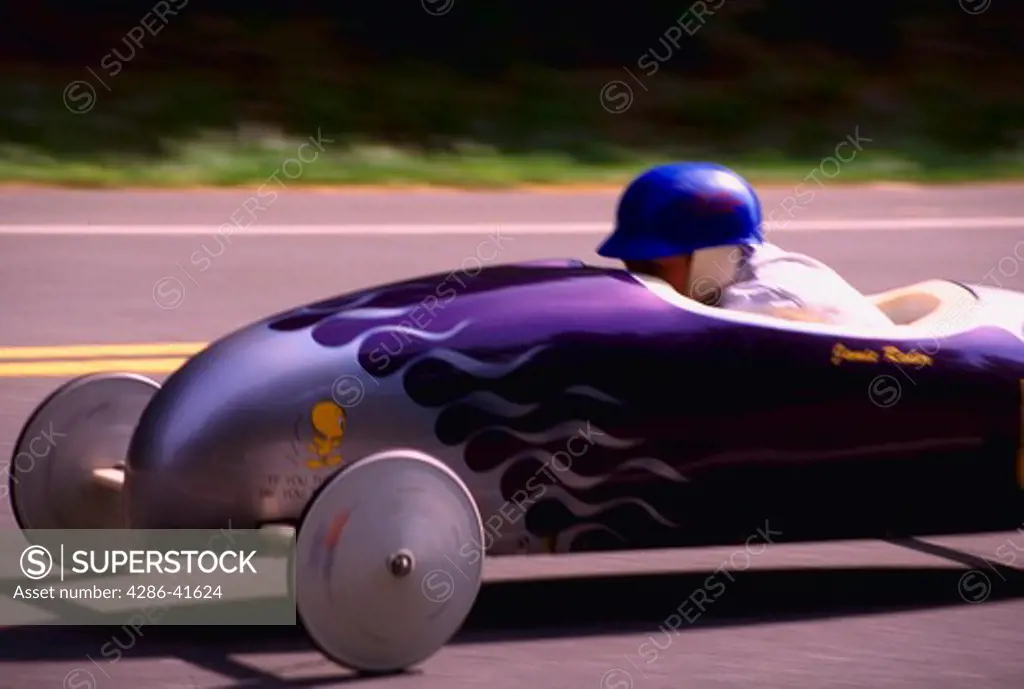 Child wearing helmet and driving purple soap box racer at Maryland Soap Box Derby, Leonardtown, Maryland.