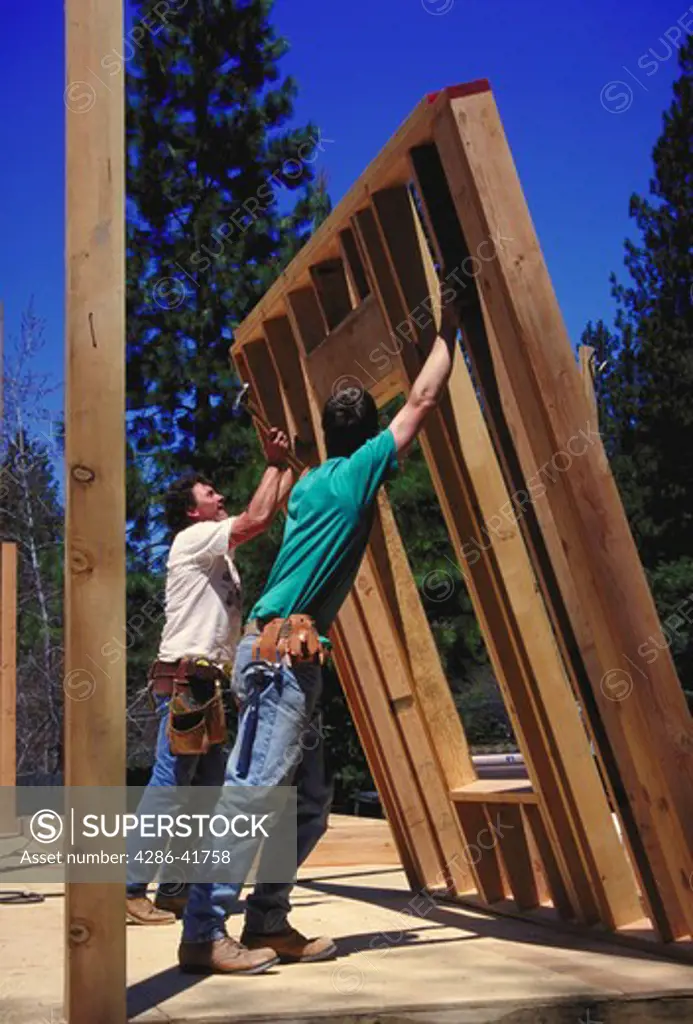 carpenters raising home wall, CA