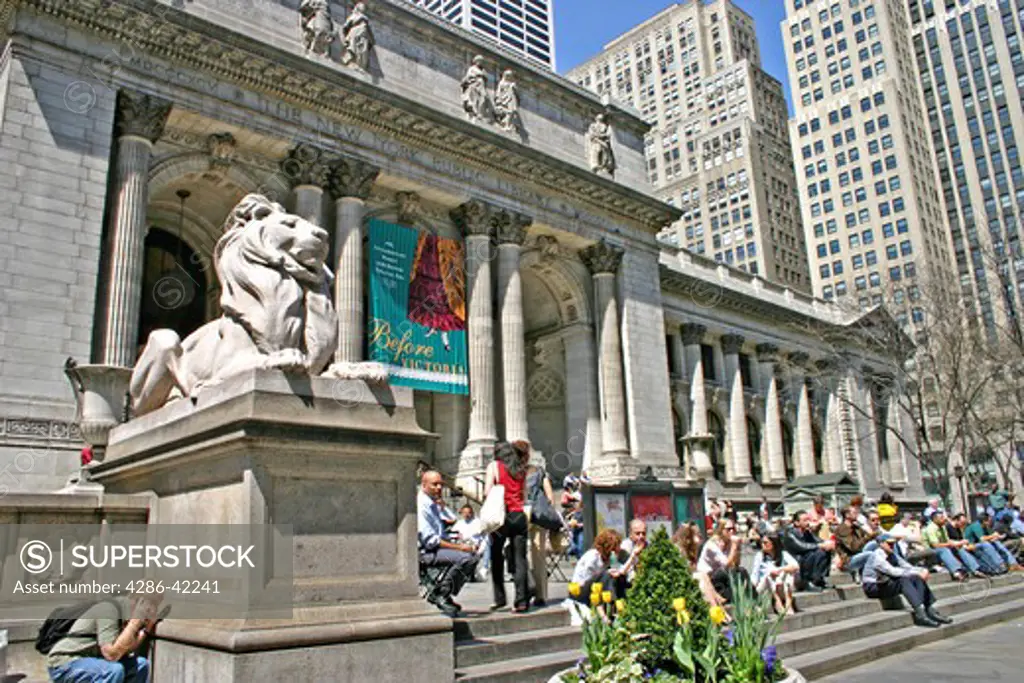 People sitting on steps sunny day New York Public Library Fifth Avenue New York City