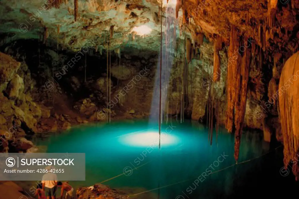 A light ray streams down onto the water inside Dzit-Nup, an underground cenote near Valladolid, Yucatan, Mexico.