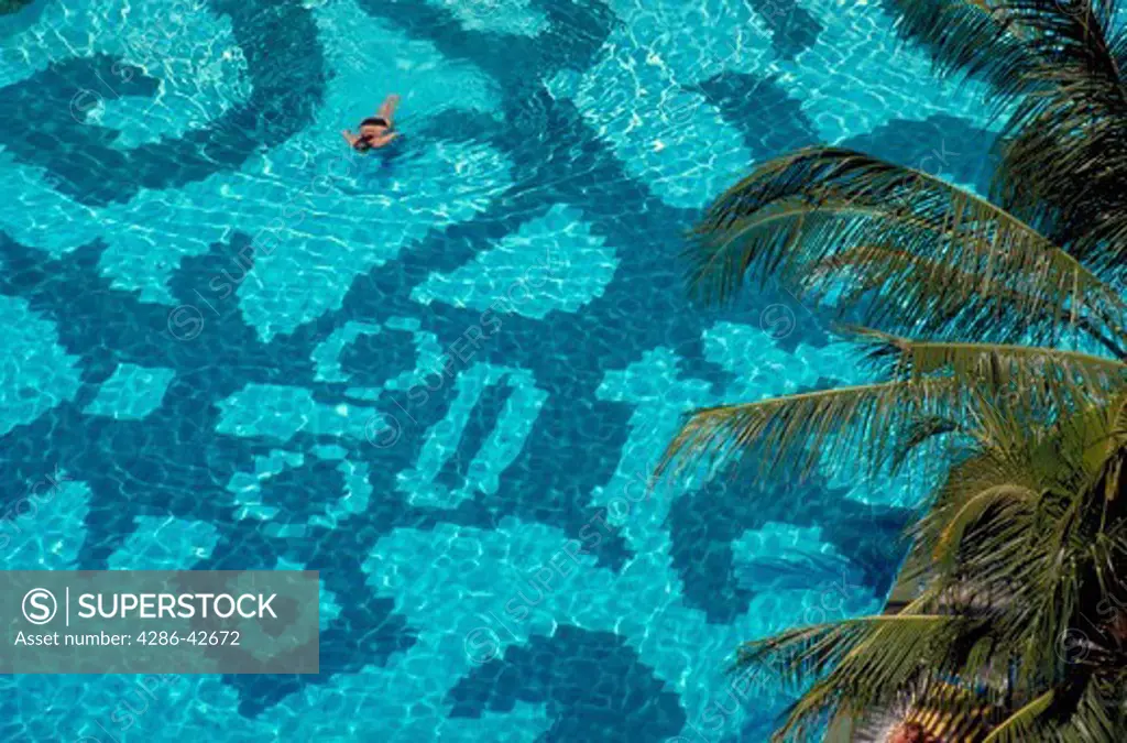 Aerial view of a person swimming over the detailed design on the bottom of the pool at the Grand Bali Beach Hotel, Indonesia.