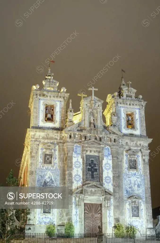 The facade of the church of St. Idelfonso with its blue and white tile work is illuminated at night in Porto, Portugal.