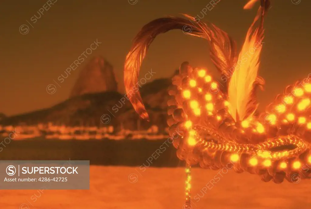 Silhouette view of Sugarloaf Mountain in Rio de Janeiro, Brazil with a ballroom mask superimposed on the photo.