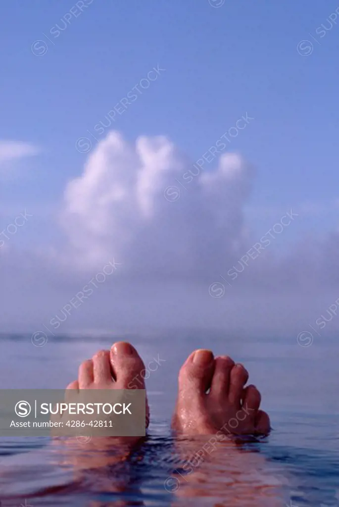 Persons feet sticking out of the water.
