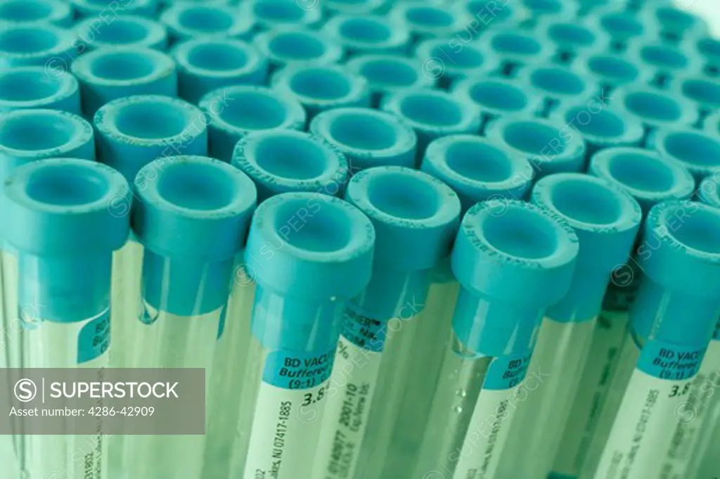 Close-up of a group of stacked medical vials with blue rubber stoppers.